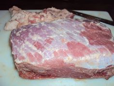 a piece of meat sitting on top of a white cutting board next to a knife