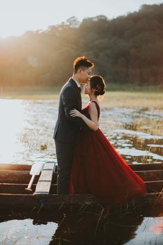 a man and woman standing on top of a wooden boat in the middle of water