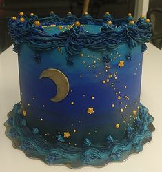 there is a blue cake with gold stars and a crescent on the top, sitting on a table