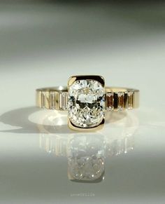 an oval cut diamond ring with baguettes in yellow gold setting on a reflective surface