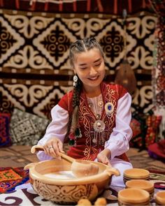 a woman in traditional clothing is making pancakes on a table with other items around her