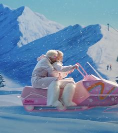 a woman riding on the back of a pink sled down a snow covered slope