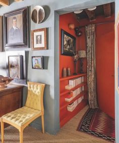 a room with blue walls and pictures on the wall, including a chair in front of a bookshelf