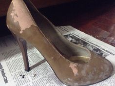 a pair of dirty high heels sitting on top of a newspaper next to a wooden table