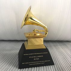 an award is displayed on a bed with a white sheet in the background and a gold phonograph