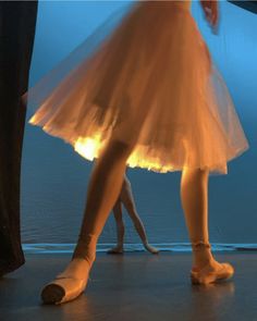 two dancers in white tutus and ballet shoes with their feet on the dance floor