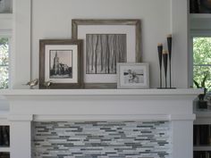 a white fireplace with pictures and frames on it's mantel above the mantle