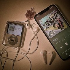 an ipod and headphones are on a table next to a cell phone with ear buds