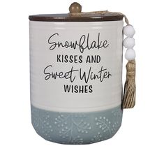 a ceramic jar with a tassel hanging from it's side that says snowflake kisses and sweet winter wishes