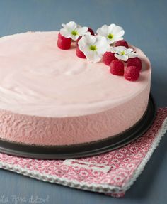 a cake with pink frosting and white flowers on top, sitting on a napkin