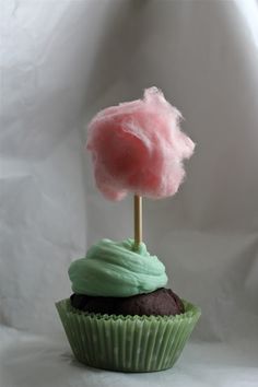 a cupcake with green frosting and a pink cloud on top is shown in front of a white background