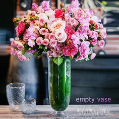 a vase filled with pink and white flowers on top of a table next to two glasses