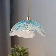 a blue and white glass light hanging from a ceiling fixture in a room with a potted plant