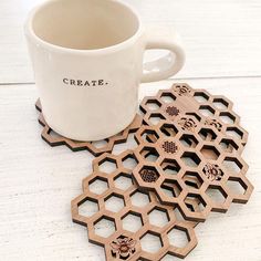 a coffee cup sitting on top of a white table next to coasters that spell create