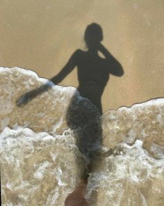 a shadow of a person standing on the beach