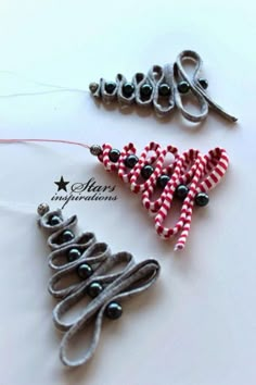 two christmas tree ornaments made out of ribbon and beads on a white surface with the word merry written in black letters