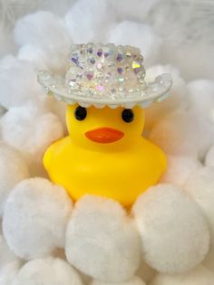 a yellow rubber duck with a crystal crown on its head sitting in white fluffy balls