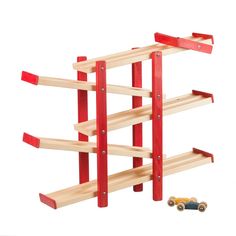 a wooden toy set with cars on the floor and two red pegs attached to it