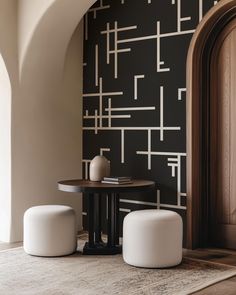 two white stools sitting on top of a rug in front of a black wall