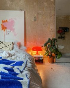 a bedroom with a bed, plant and pictures on the wall above it in an abandoned building