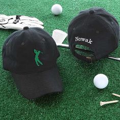 two hats and golf equipment on the ground next to some tees, balls and clubs