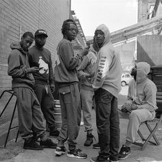 black and white photograph of four young men standing on the sidewalk with an accordion in front of them