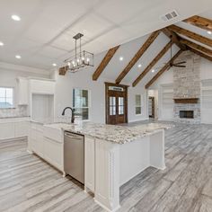 a large kitchen with an island in the middle and wood beams on the ceiling above it