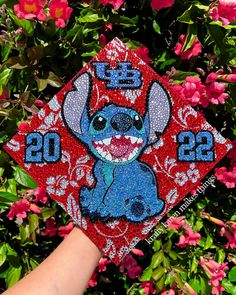 someone is holding up a graduation cap with stitching on it and lil the disney mouse