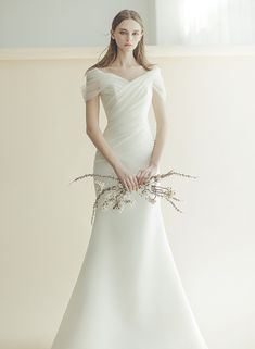 a woman in a white wedding dress holding flowers