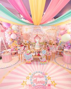 a room filled with lots of balloons and tables covered in pink, yellow and blue decorations