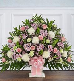 a pink and white flower arrangement in a vase