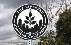 a sign for the riverbed anaheim california with trees and power lines in the background