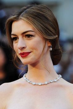 a woman in a strapless dress with red lipstick on her lips and wearing a diamond necklace