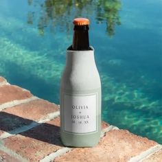 a bottle sitting on top of a brick wall next to the water with a tree in the background