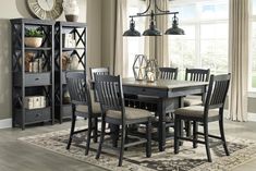 a dining room table and chairs with a clock on the wall behind it in front of a window