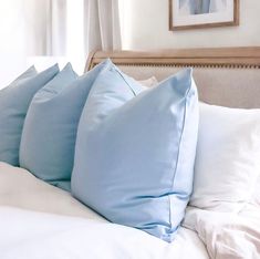 four blue pillows on top of a white bed