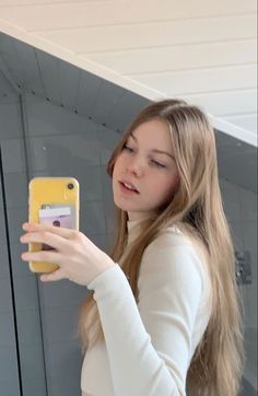 a woman is taking a selfie with her cell phone while standing in front of a mirror