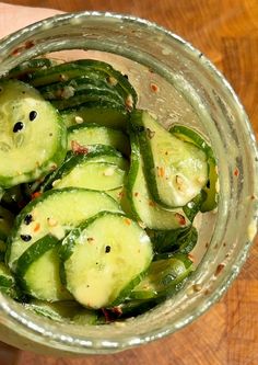 cucumber slices in a glass bowl on a wooden table with pepper flakes