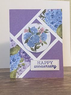 a purple and white card with blue flowers on it that says happy anniversary in the center