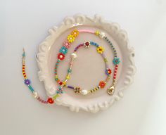 a white plate topped with lots of colorful beaded bracelets next to a necklace