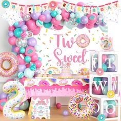 a table topped with donuts and balloons next to a sign that says two sweet shop