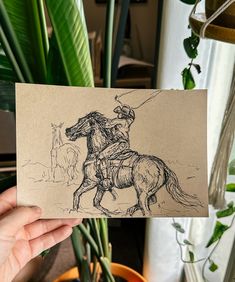 a person holding up a card with a drawing of a man riding a horse on it