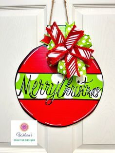 a red and green christmas ornament hanging from a door with a bow on it