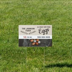 an egg sign is in the grass with eggs on it's stick and another sign behind it that says, the johnson family farm