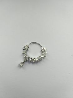 a small silver nose ring with flowers on the side and pearls hanging from it's end