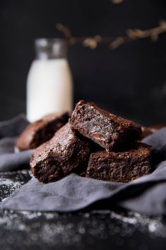 chocolate brownies on a napkin next to a glass of milk