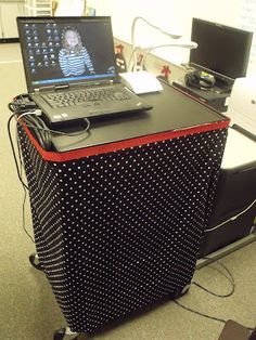 an open laptop computer sitting on top of a black and red box with white dots