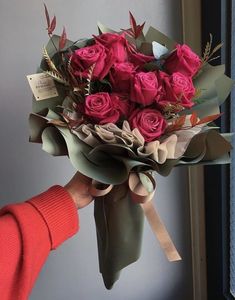 a person holding a bouquet of red roses