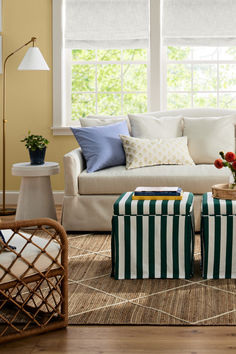 a living room filled with furniture next to a window covered in white and blue pillows