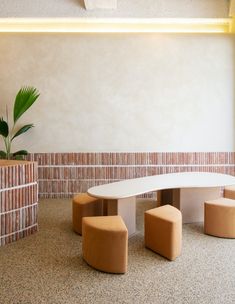 a bench and two stools in a room with brick walls, plants and potted plant